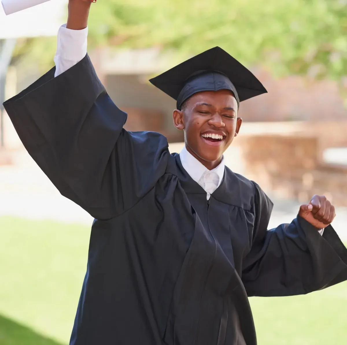 A graduate celebrating while holding up a diploma